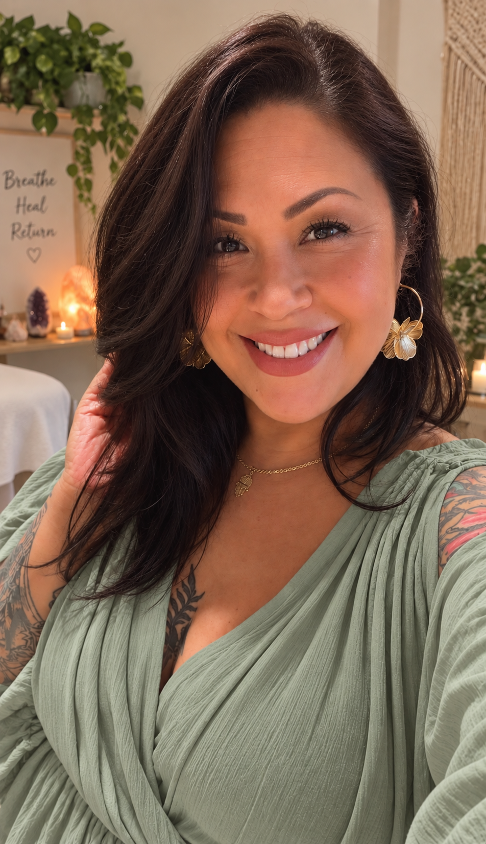 Natisa Rosco, founder of The Sacred Inhale, smiling in a sage green wrap top beside plants, a salt lamp, candle, amethyst, and a Breathe Heal Return sign